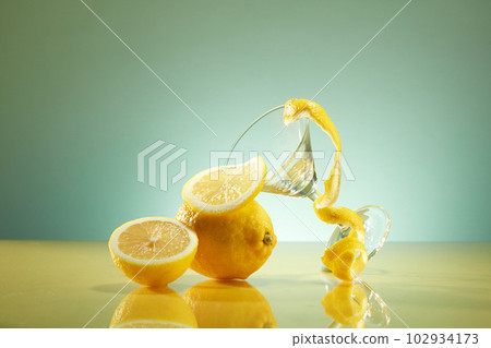 Fresh lemon and lemon slices decorated with glass cup and lemon peel on back-lit background. Scene for a product commercial featuring a lemon component Fresh lemon and lemon slices decorated with glass cup and lemon peel on back-lit background. Scene for a product commercial featuring a lemon component 102934173