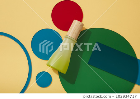 Minimalist art background for product presentation - green bottle with wooden cap unlabeled decorated on beige background with colorful acrylic sheets. Space for design 102934717