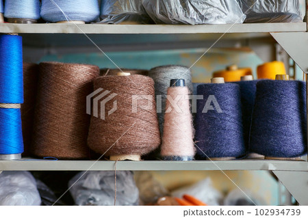 Bobbins with knitted threads stand in a row on the rack 102934739