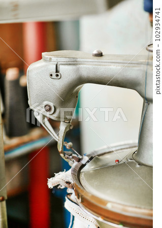 A small simple knitting machine with threads nearby without workers 102934741