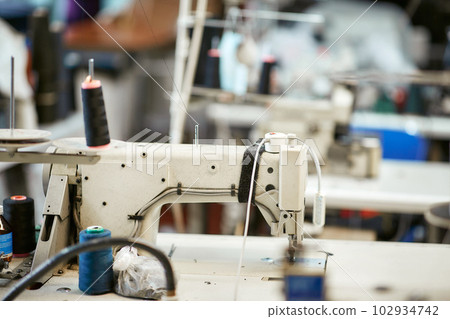 White sewing machine with threads nearby without workers 102934742