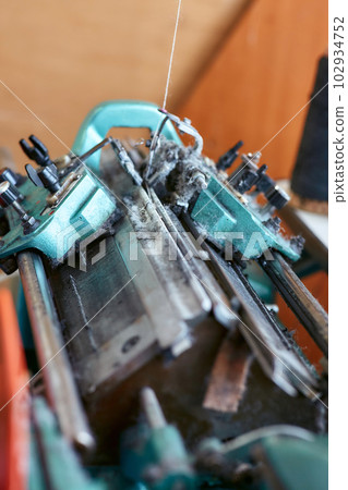 A small simple knitting machine with threads nearby without workers 102934752