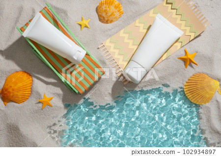 Colorful origami chair and carpet with two empty label tube placed on, decorated with yellow seashells and starfishes. Summer view 102934897