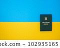 Ukrainian green military ID ticket on the Ukrainian national flag in the top view. Translation 102935165