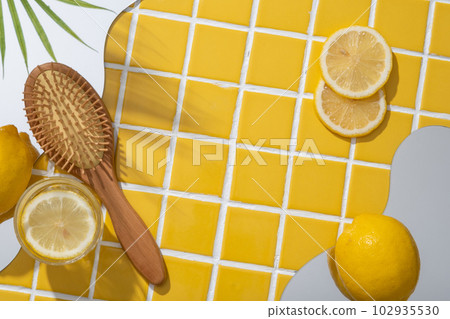 A wooden brush displayed with geometric mirrors and Lemon slices. Lemon (Citrus limon) is high in vitamin C that can help whitening skin. Blank space to show beauty product extracted from Lemon 102935530