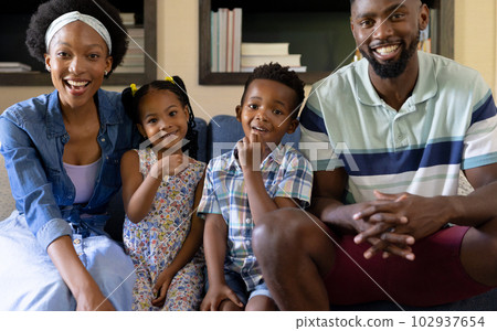 Portrait of smiling african american parents and children sitting on sofa in living room at home Portrait of smiling african american parents and children sitting on sofa in living room at home 102937654