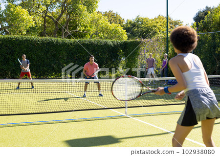 Happy diverse group of friends playing tennis at tennis court Happy diverse group of friends playing tennis at tennis court 102938080