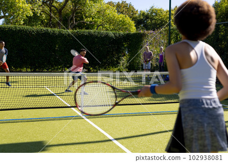 Happy diverse group of friends playing tennis at tennis court Happy diverse group of friends playing tennis at tennis court 102938081