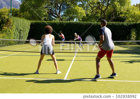 Happy diverse group of friends playing tennis at tennis court Happy diverse group of friends playing tennis at tennis court 102938092