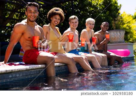 Portrait of happy diverse group of friends having pool party, holding plastic cups in garden Portrait of happy diverse group of friends having pool party, holding plastic cups in garden 102938180