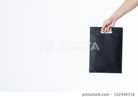 Hand of caucasian woman holding black bag with copy space on white background 102940358