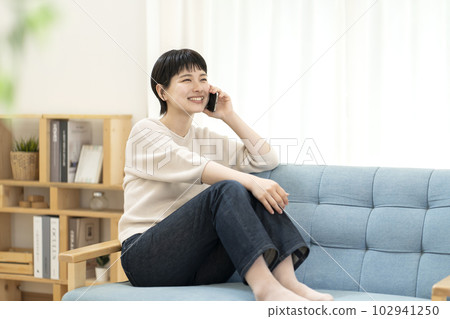 坐在沙發上打電話的年輕女人 102941250