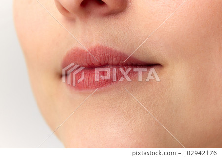 Portrait with low part of young female face with thin lips over white background. Bullhorn lip lift Portrait with low part of young female face with thin lips over white background. Bullhorn lip lift 102942176