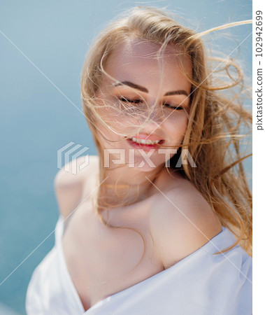 Portrait of a blond woman at the sea, a woman makes photos for memory from a trip to the sea to show to friends. Portrait of a blond woman at the sea, a woman makes photos for memory from a trip to the sea to show to friends. 102942699