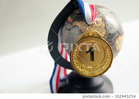 Gold medal in the foreground on red blue white ribbon 102943254