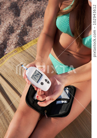 An independent child checks the level of glucose in the blood while sitting on the beach. An independent child checks the level of glucose in the blood while sitting on the beach. 102943612