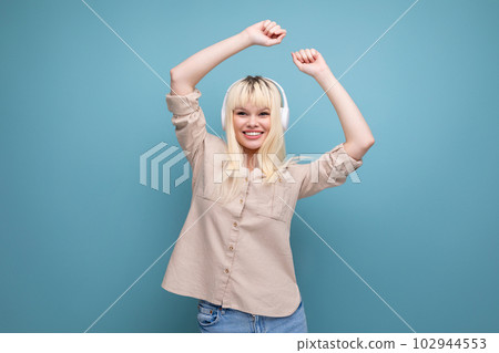 charming blonde young girl loves to listen to podcast with headphones 102944553