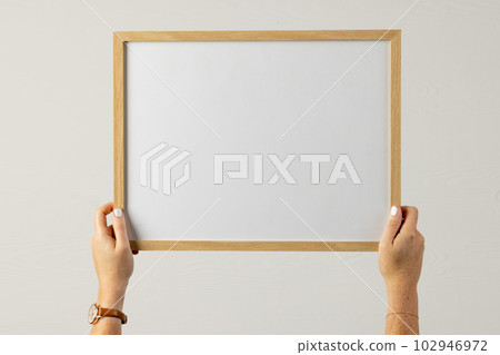 Hands holding wood empty frame with copy space against white wall Hands holding wood empty frame with copy space against white wall 102946972