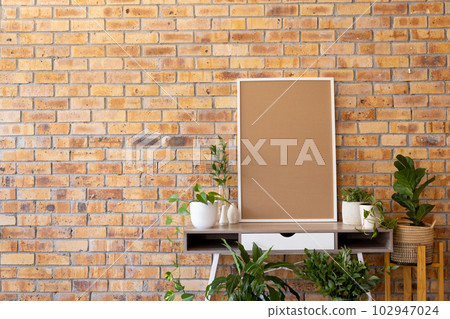 White empty frame with copy space and plants in pots on desk against brick wall White empty frame with copy space and plants in pots on desk against brick wall 102947024