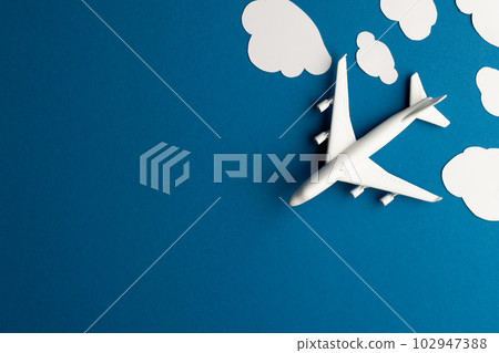 Close up of airplane model with clouds on blue background with copy space Close up of airplane model with clouds on blue background with copy space 102947388