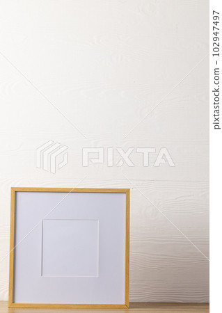 Vertical of empty wooden frame with copy space on table against white wall 102947497