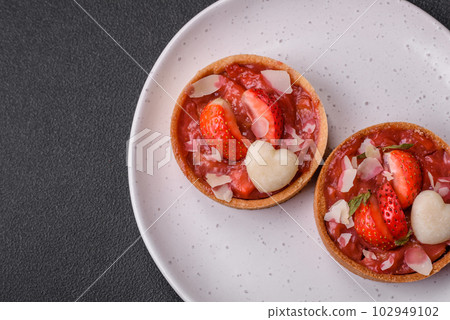 Delicious fresh sweet tartlets with strawberries and coconut flakes 102949102