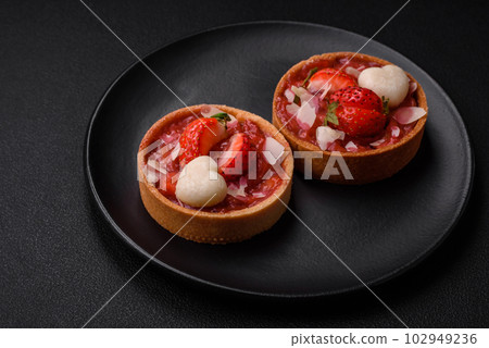 Delicious fresh sweet tartlets with strawberries and coconut flakes 102949236