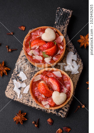 Delicious fresh sweet tartlets with strawberries and coconut flakes 102949265