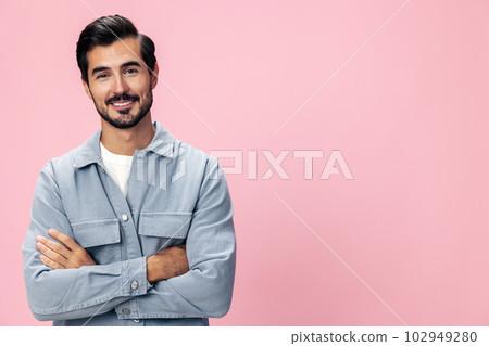 Portrait of a stylish brunette man with a beard looking into the camera on a pink background in a white T-shirt and jeans smile and joyful emotion on his face, copy space Portrait of a stylish brunette man with a beard looking into the camera on a pink background in a white T-shirt and jeans smile and joyful emotion on his face, copy space 102949280