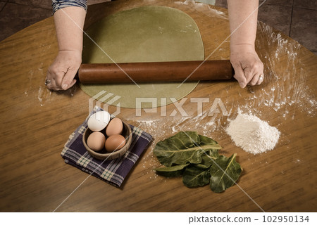 Grandma's hands kneading, dough for green noodles. 102950134