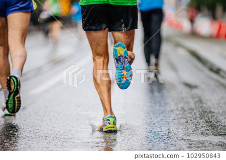 legs male runner athlete run marathon race on wet asphalt, water drops on sole running shoes legs male runner athlete run marathon race on wet asphalt, water drops on sole running shoes 102950843