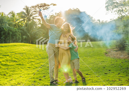 Pregnant mom, dad and son at the gender party on the golf course release blue smoke. Gender reveal announcement on the golf course. Loving family expecting baby boy. Happy moments 102952269