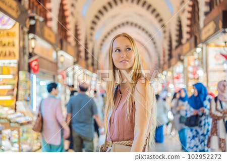 A tourist woman walks among the countless shops at the Grand Bazaar and Egyptian Bazaar in Istanbul. Shopping and travel in Turkey concept. Istanbul historical Egyptian Bazaar. Misir Carsisi, spice A tourist woman walks among the countless shops at the Grand Bazaar and Egyptian Bazaar in Istanbul. Shopping and travel in Turkey concept. Istanbul historical Egyptian Bazaar. Misir Carsisi, spice 102952272