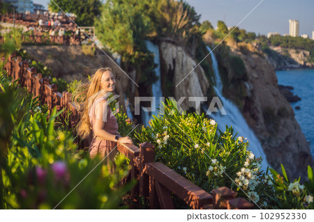 Beautiful woman with long hair on the background of Duden waterfall in Antalya. Famous places of Turkey. Lower Duden Falls drop off a rocky cliff falling from about 40 m into the Mediterranean Sea in 102952330