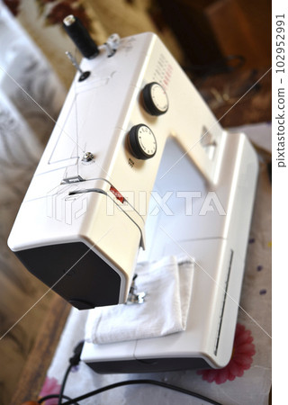 A white sewing machine in the room. Processing of clothes with a sewing machine. A white sewing machine in the room. Processing of clothes with a sewing machine. 102952991