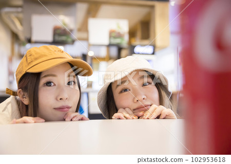 Snowboarding girls looking out from the cafe table Snowboarding girls looking out from the cafe table 102953618