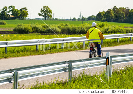 Cycling outdoor, elderly woman in a yellow vest riding a bicycle Cycling outdoor, elderly woman in a yellow vest riding a bicycle 102954493
