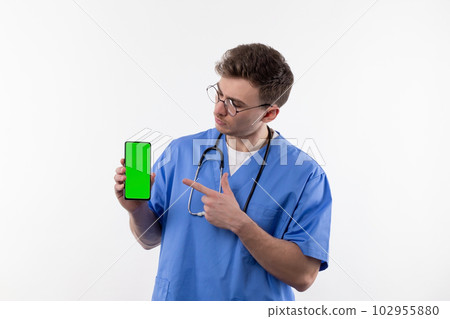 Doctor nurse in uniform and with a stethoscope points to a smartphone with a green screen advertising medical pharmacology  102955880
