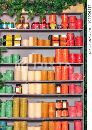 Scented multi-colored candles are stacked on the shelves of a gray stand. Scented multi-colored candles are stacked on the shelves of a gray stand. 102956115