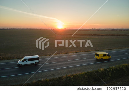 Aerial view of intercity road with fast driving cars at sunset. Top view from drone of highway traffic in evening Aerial view of intercity road with fast driving cars at sunset. Top view from drone of highway traffic in evening 102957520