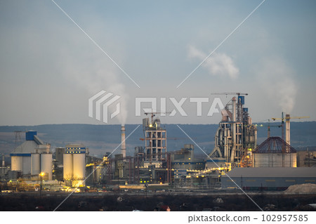 Aerial view of cement factory with high concrete plant structure and tower cranes at industrial production area at night. Manufacture and global industry concept 102957585