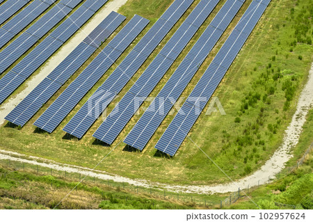 Aerial view of big sustainable electric power plant with many rows of solar photovoltaic panels for producing clean electrical energy. Renewable electricity with zero emission concept 102957624