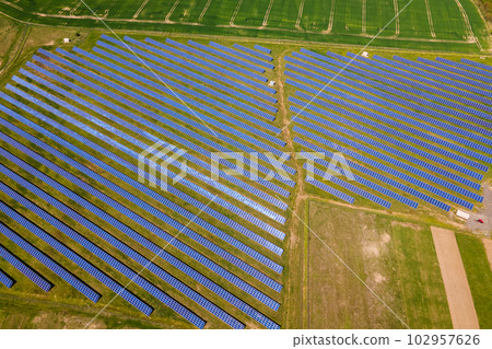 Aerial view of big sustainable electric power plant with many rows of solar photovoltaic panels for producing clean ecological electrical energy. Renewable electricity with zero emission concept. 102957626