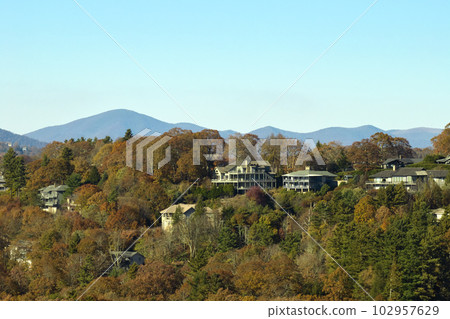 Aerial view of big family houses on mountain top between yellow trees in North Carolina suburban area in fall season. Real estate development in american suburbs 102957629