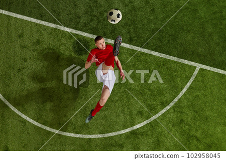 One professional football soccer player in uniform kicking the ball from penalty mark over green grass field background. Concept of professional sport One professional football soccer player in uniform kicking the ball from penalty mark over green grass field background. Concept of professional sport 102958045