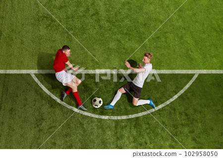 Aerial view of soccer football players in sports uniform and football boots battling for the ball over green grass field background 102958050