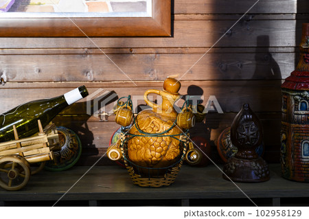 Clay jugs of wine on a wooden shelf in the sunset Clay jugs of wine on a wooden shelf in the sunset 102958129