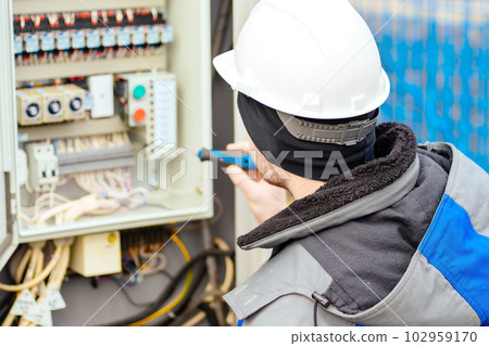 Instrumentation and automation engineer in white hard hat checks equipment. Real workflow. Back view Instrumentation and automation engineer in white hard hat checks equipment. Real workflow. Back view 102959170