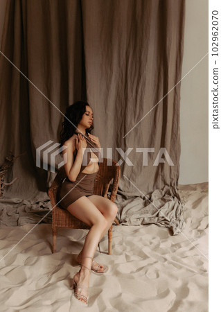 Attractive model posing in studio with sea sand. Attractive model posing in studio with sea sand. 102962070