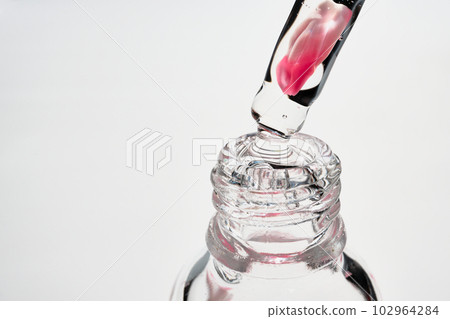 Serum bottle and pipette with rose petal close-up. Floral cosmetic product, selective focus Serum bottle and pipette with rose petal close-up. Floral cosmetic product, selective focus 102964284